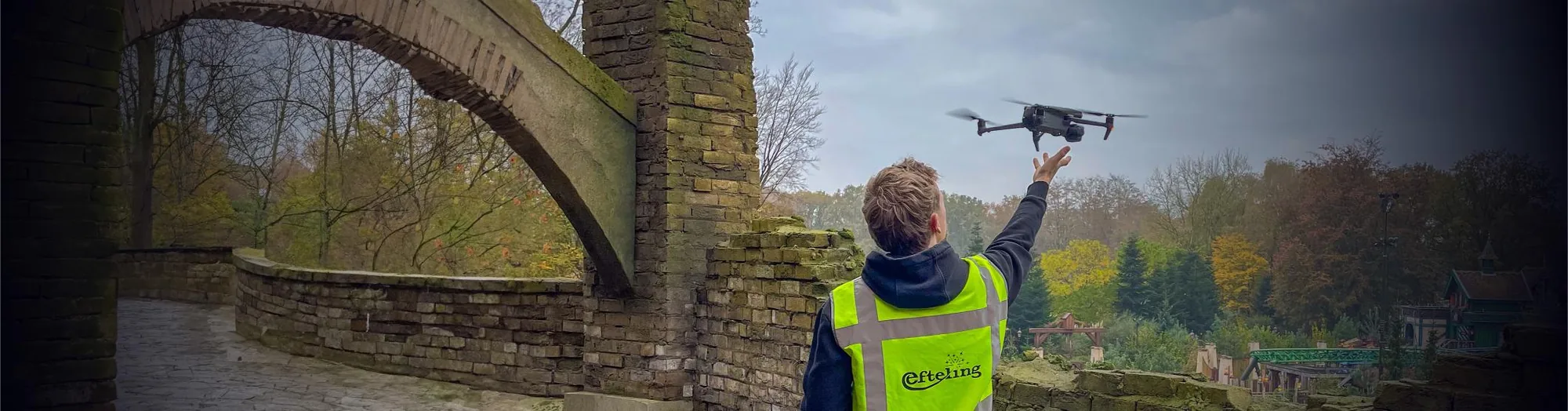 Crew met Efteling-veiligheidshesje lanceert een Mavic-drone bij het bouwterrein