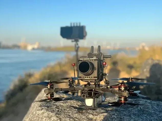 FPV-drone met cinema-camera bij een rivier, gereed voor opname