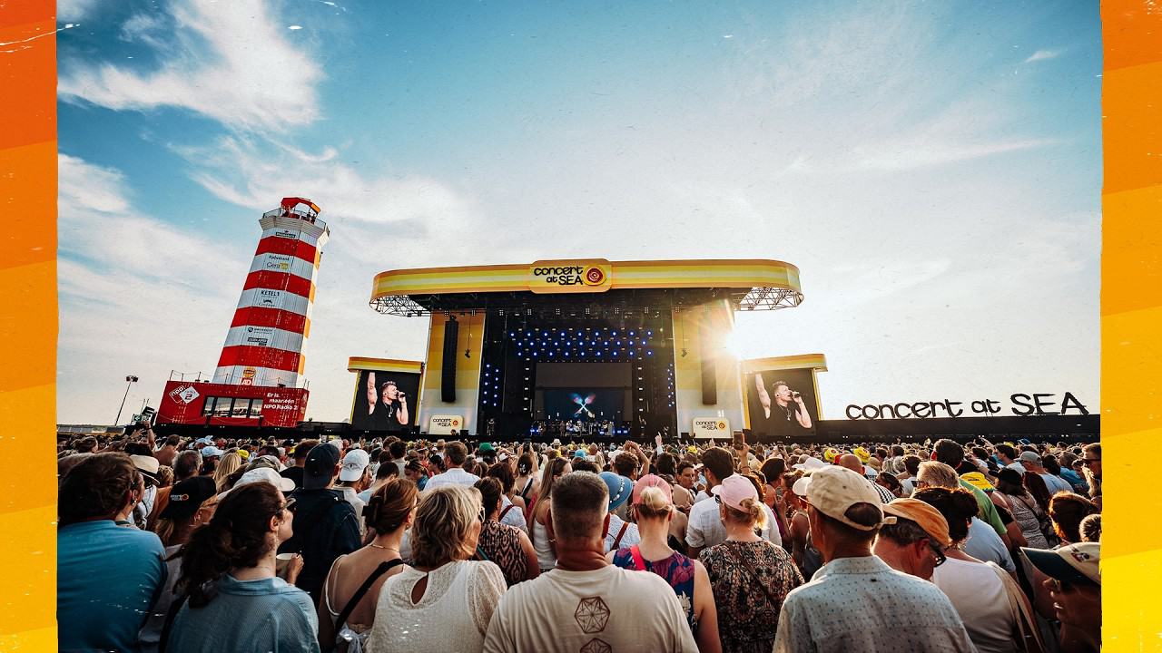 Het hoofdpodium van Concert at SEA op de Brouwersdam, met de vuurtoren en een volle menigte